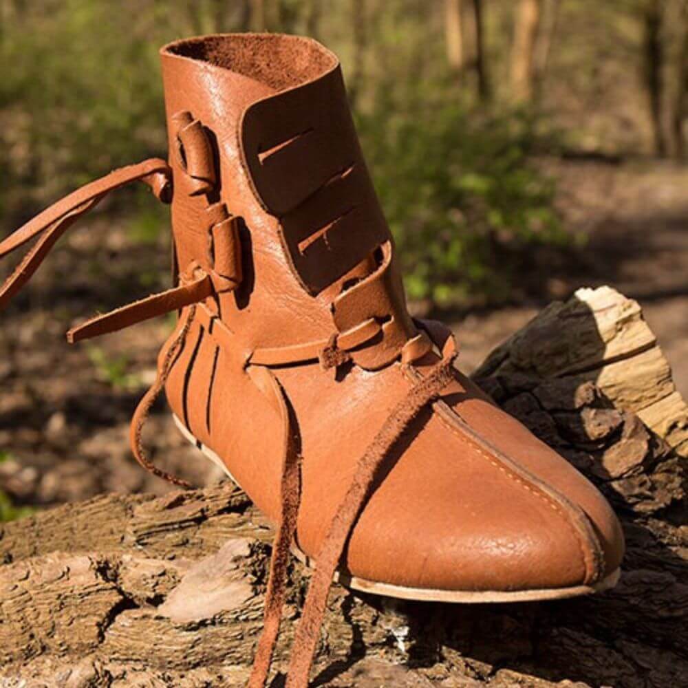 Close-up of Thor’s Leather Viking Boots on a log, featuring rustic stitching and traditional Viking-style lacing.