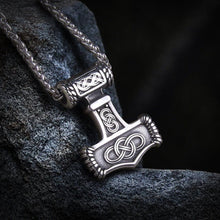 Silver Viking Thor's Hammer Mjolnir necklace with intricate Celtic knotwork design on a dark, textured surface.
