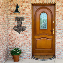 Viking Thor's Hammer Mjolnir metal wall sign in black, featuring intricate Celtic knotwork, on a brick wall.