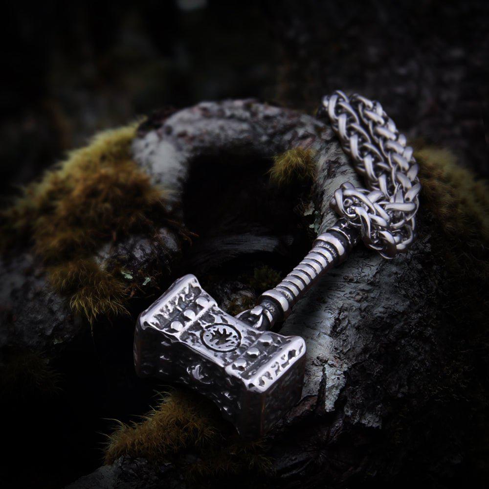 Rugged silver Viking Thor's Hammer pendant with intricate chain, resting on mossy wood.