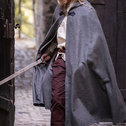 Grey wool Viking cloak with a black wolf clasp, worn by a person holding a sword.