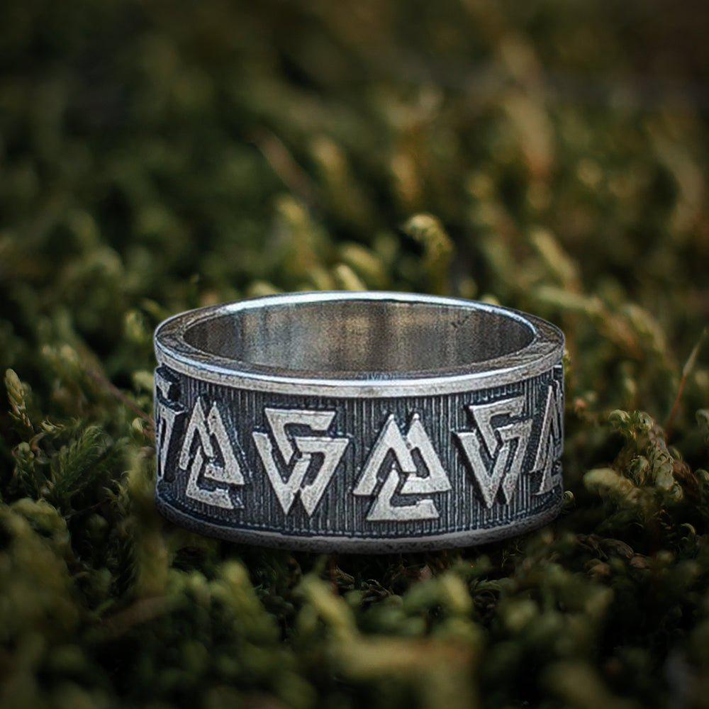 Sterling silver Viking Valknut symbol ring with dark, intricate knotwork on green moss.