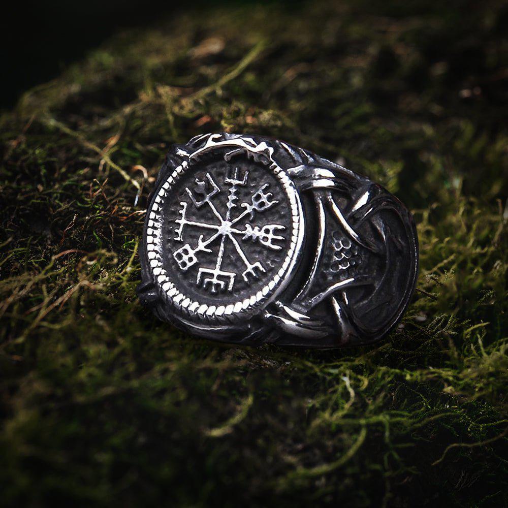 Viking Vegvisir compass ring in dark steel with Jormungandr knotwork on moss.