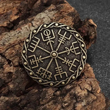 Bronze Viking Vegvisir compass brooch with Norse protection symbols on bark.