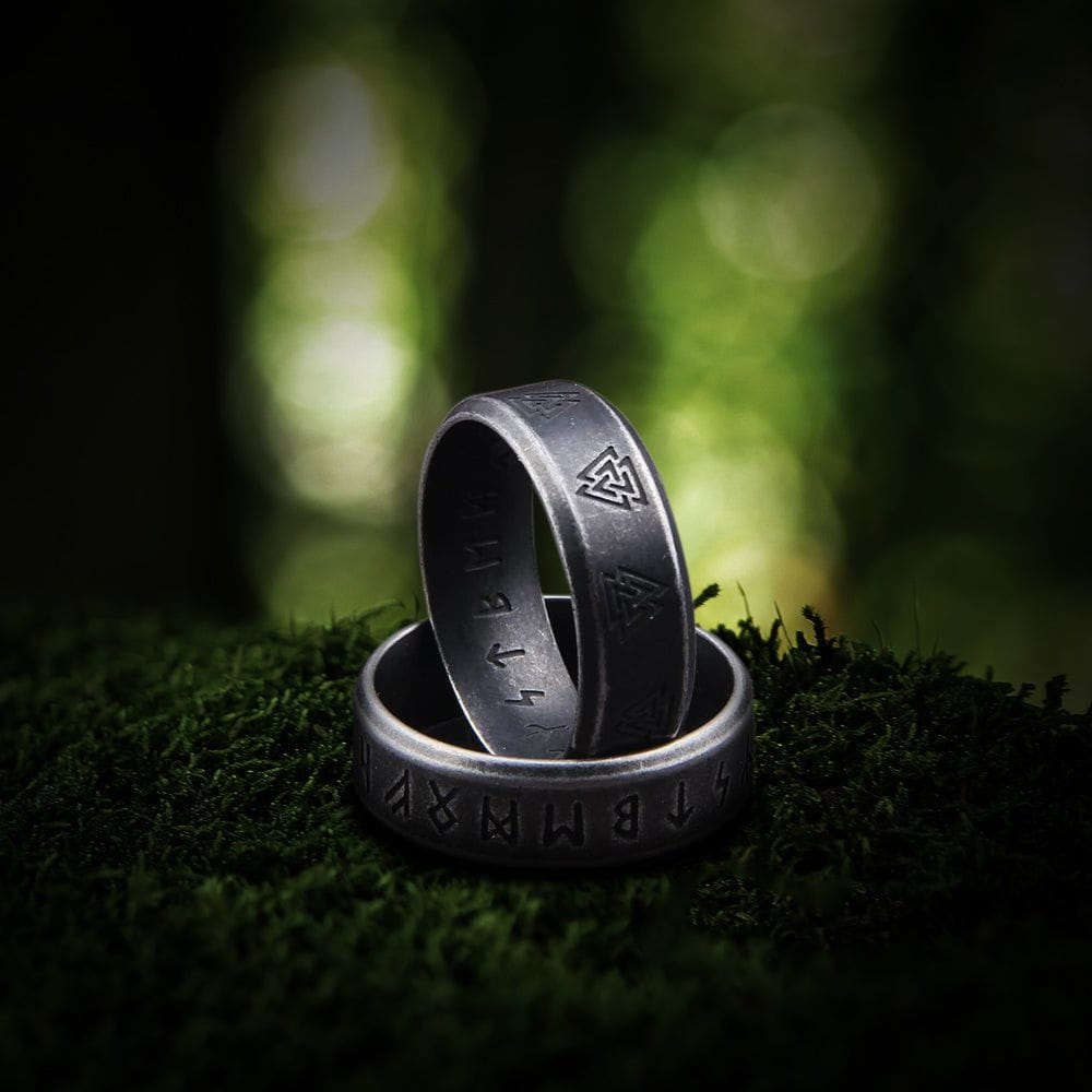Dark silver Viking ring with engraved runes and Valknut symbols on moss.