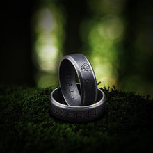 Dark silver Viking ring with engraved runes and Valknut symbols on moss.