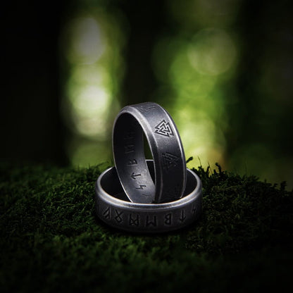 Dark silver Viking ring with engraved runes and Valknut symbols on moss.