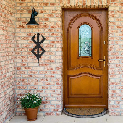 Black Viking Berserker Rune metal wall sign on a brick wall next to a wooden door.