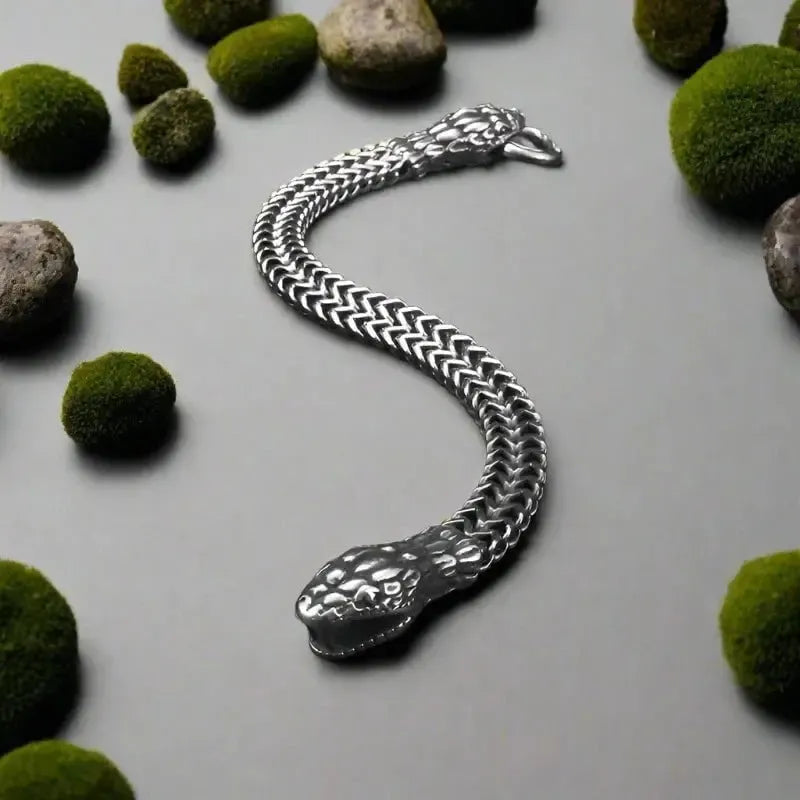 Viking silver-tone twin serpent bracelet with braided chain on a dark background with moss.