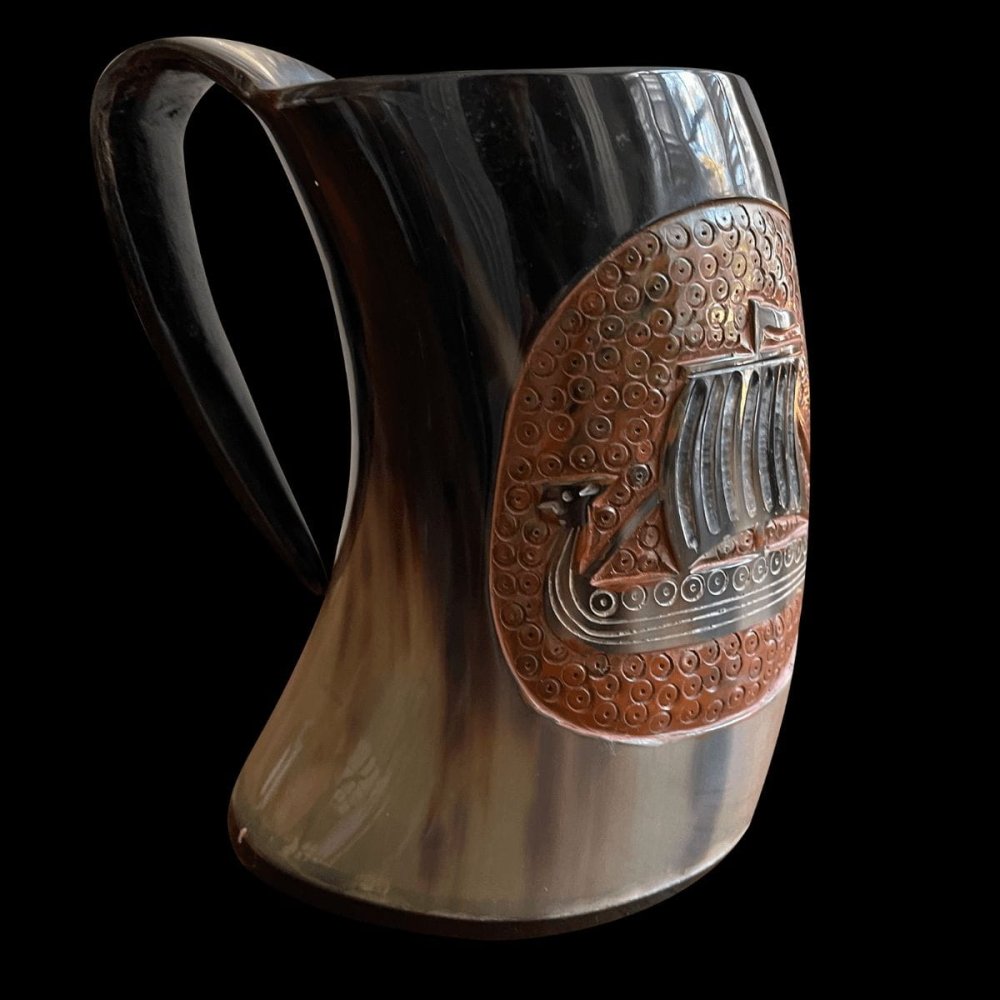 Viking drinking horn cup, dark polished horn with a carved longship on a brown textured oval.