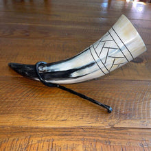 Viking drinking horn with black and white scale pattern, resting on an iron stand.