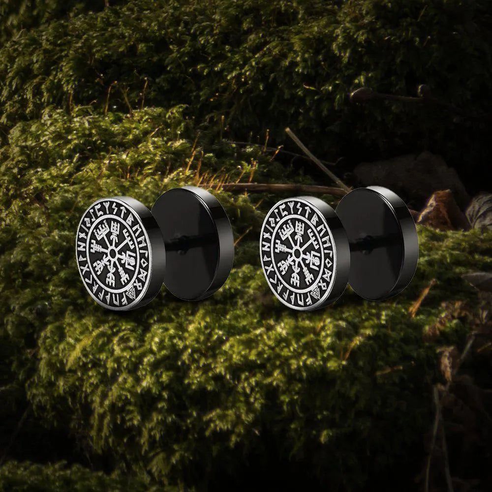 Black Viking stud earrings with white Norse Vegvisir compass symbol on mossy ground.