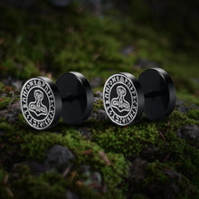 Viking black stud earrings with Thor's Hammer and runic symbols on a mossy rock.