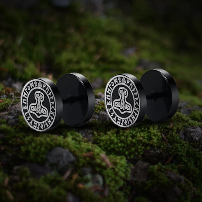 Viking black stud earrings with Thor's Hammer and runic symbols on a mossy rock.