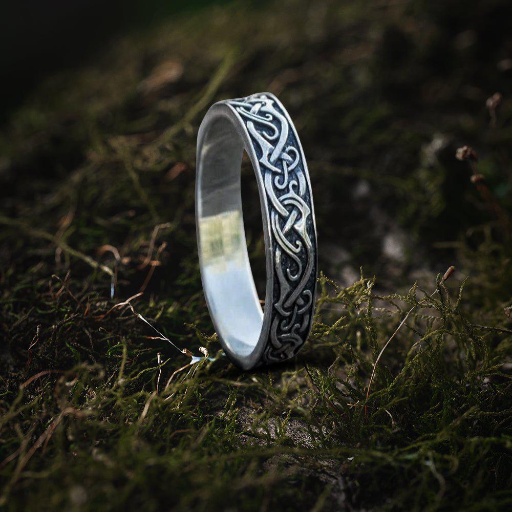 Silver Viking ring with intricate Celtic knotwork design on moss.