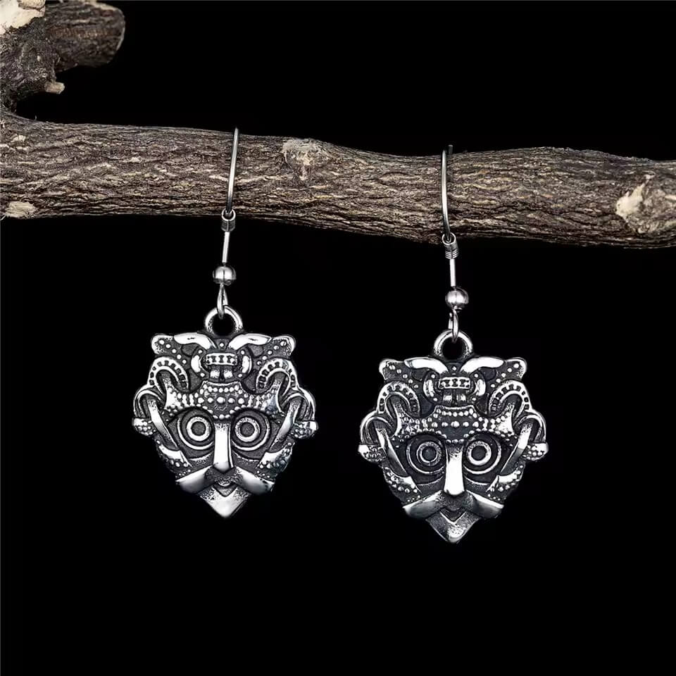 Viking Odin mask stainless steel earrings with intricate details, hanging from a branch.
