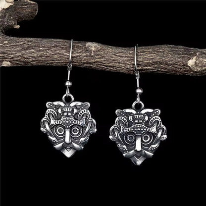 Viking Odin mask stainless steel earrings with intricate details, hanging from a branch.