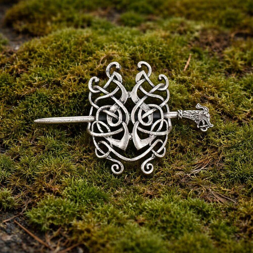 Viking silver serpent knot hair clip with intricate Celtic design and dragon head pin, on moss.