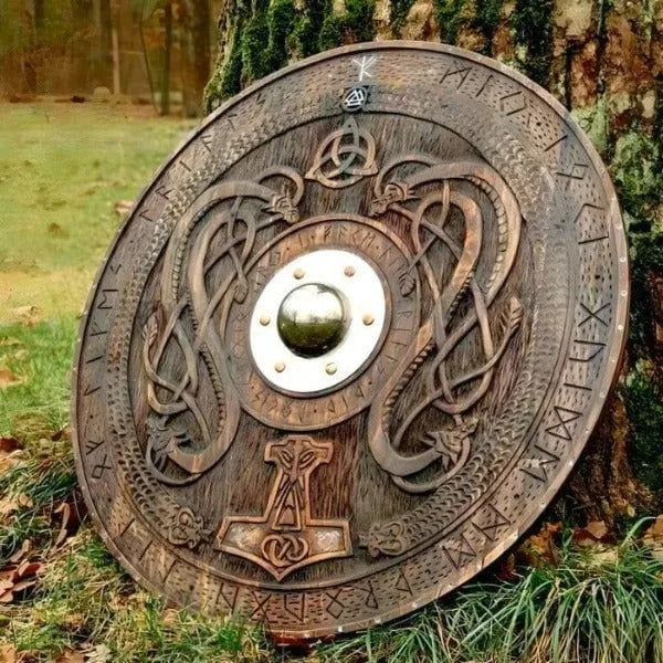 Round dark wood Viking shield with carved Norse runes, entwined dragons, Mjolnir, and a central metal boss.