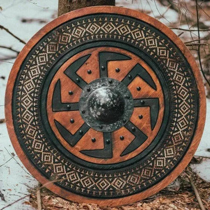 Round Viking wooden shield with carved Kolovrat symbol and metal boss.