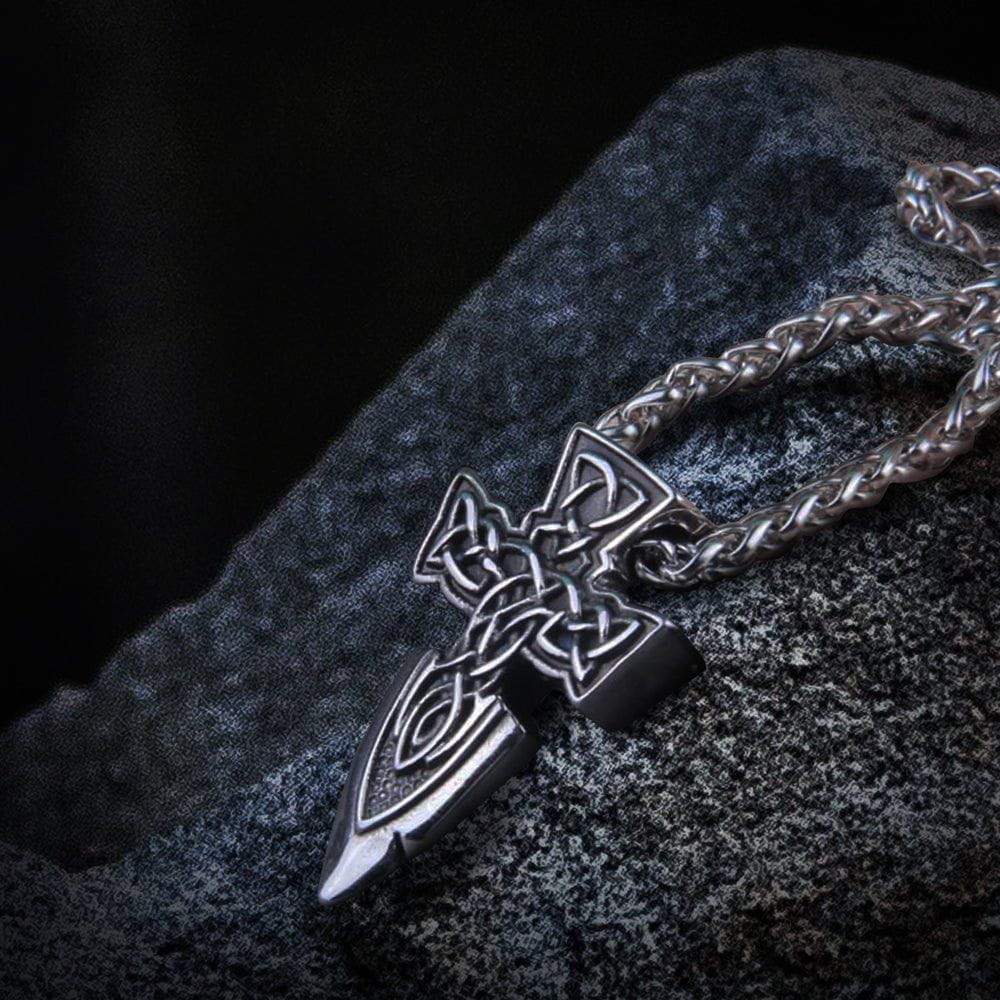 Viking silver spear point cross amulet necklace with intricate Celtic knotwork on a dark, textured surface.