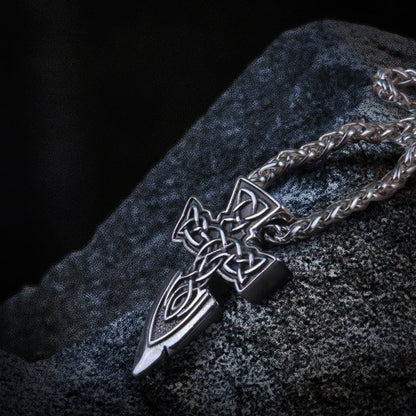 Viking silver spear point cross amulet necklace with intricate Celtic knotwork on a dark, textured surface.