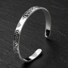 Viking sterling silver cuff bracelet with intricate Celtic spiral knotwork design on a dark surface.