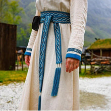 Viking blue tie belt with white braided trim and tassels on a cream dress.