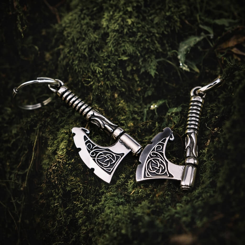Viking Triquetra axe drop earrings, silver-toned metal, resting on green moss.