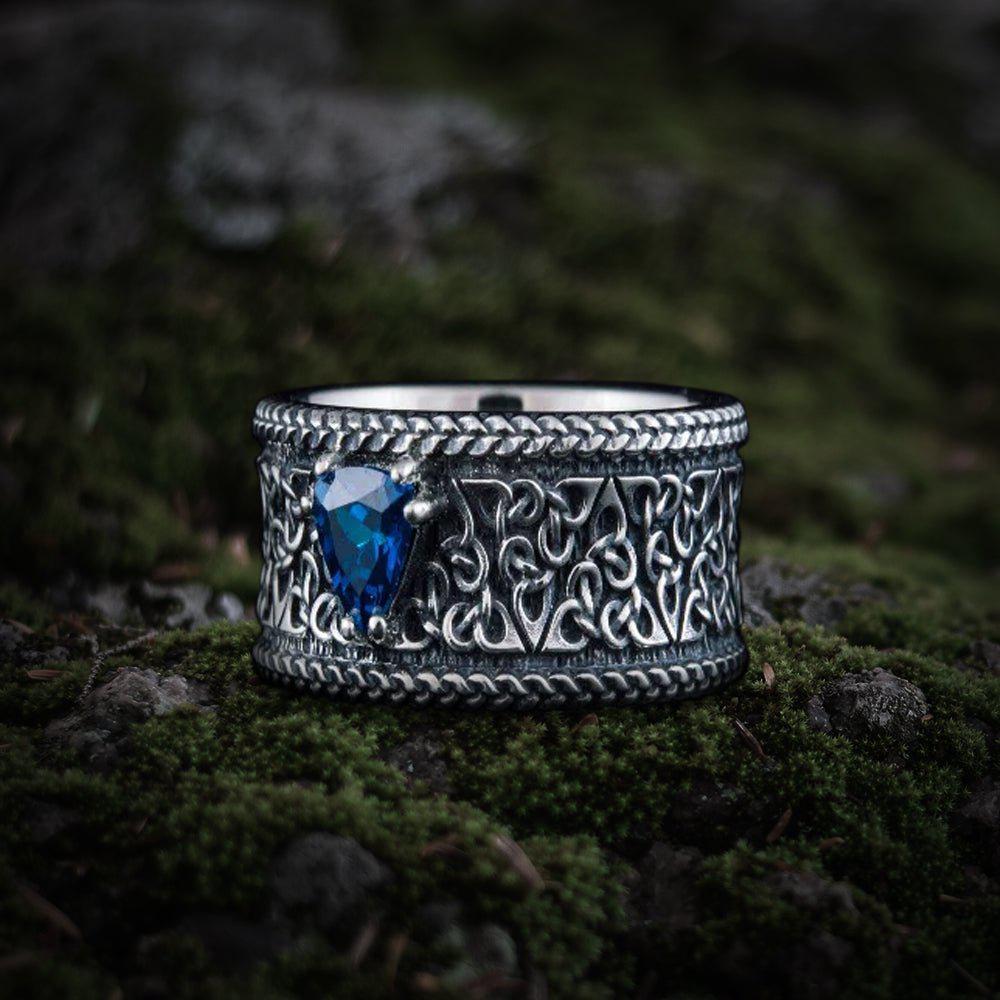 Viking sterling silver ring with intricate Celtic knotwork and a vibrant blue triangular gemstone.
