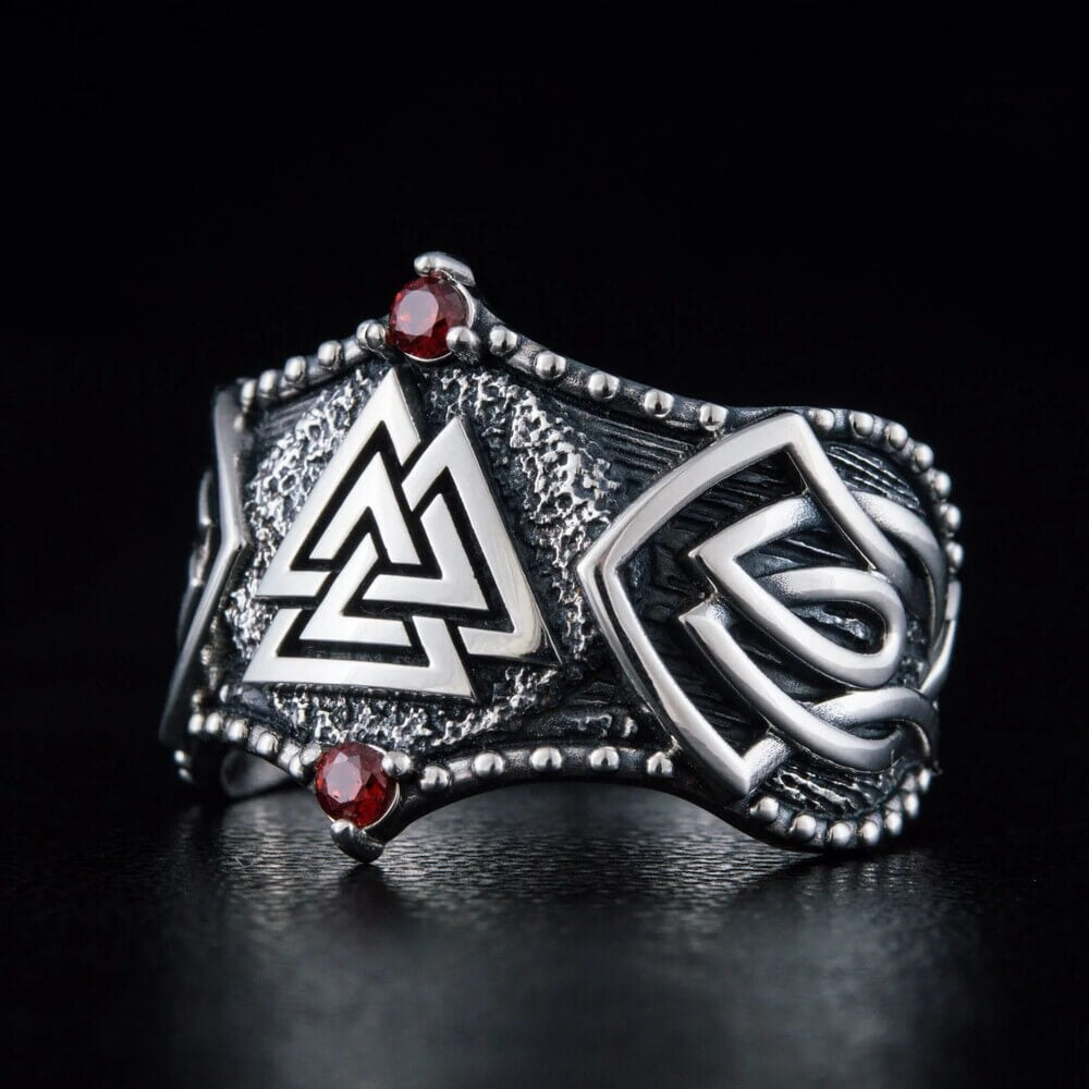Viking Valknut silver ring with red stones, intricate knotwork, and textured details.