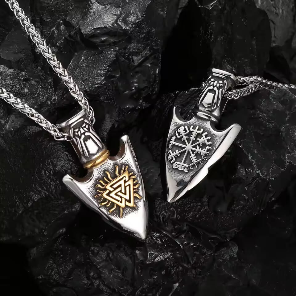 Viking Valknut Vegvisir arrowhead necklaces, silver and gold stainless steel, on a dark rock background.