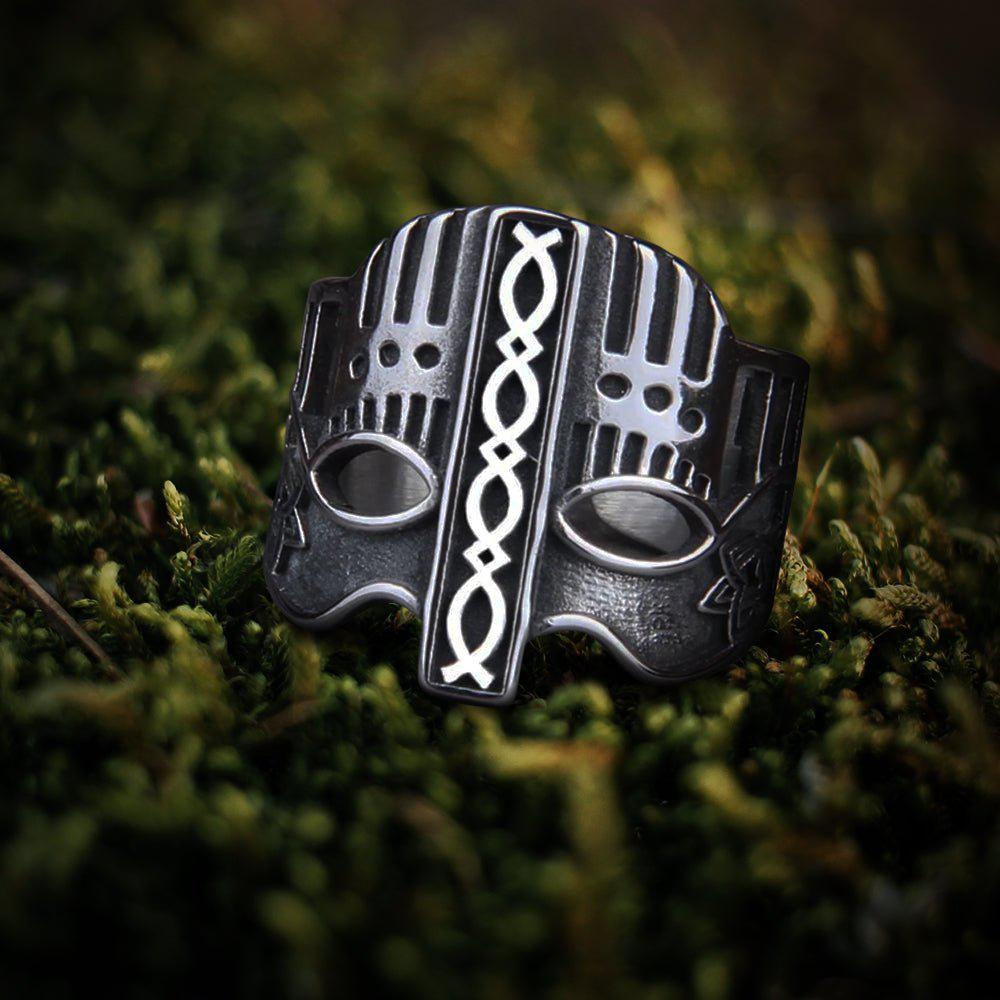 Dark silver Viking battle helm ring with white knotwork on green moss.