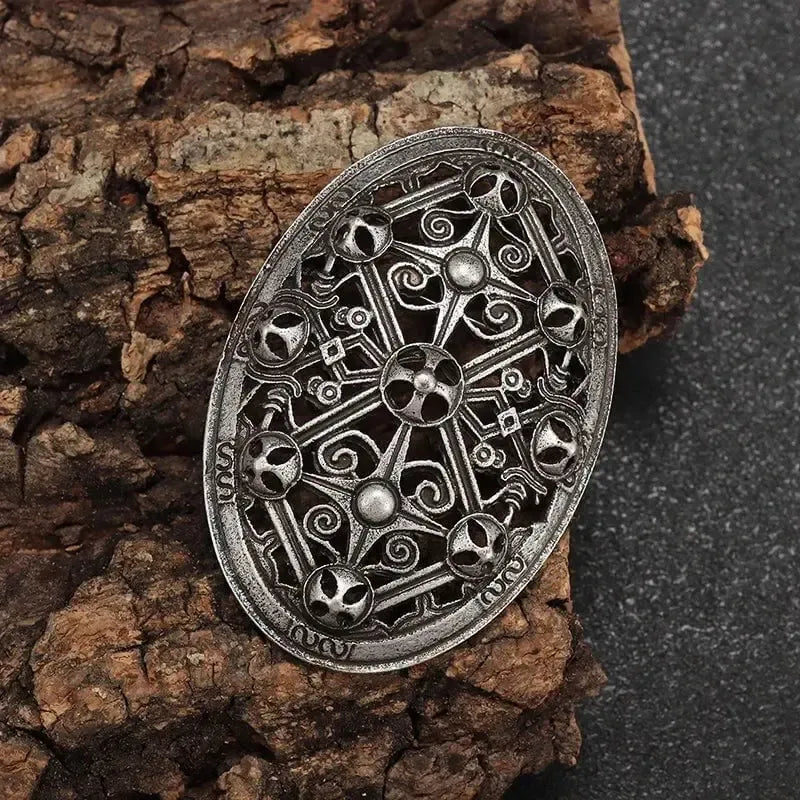 Viking oval silver brooch with intricate spiral and rune patterns on wood.