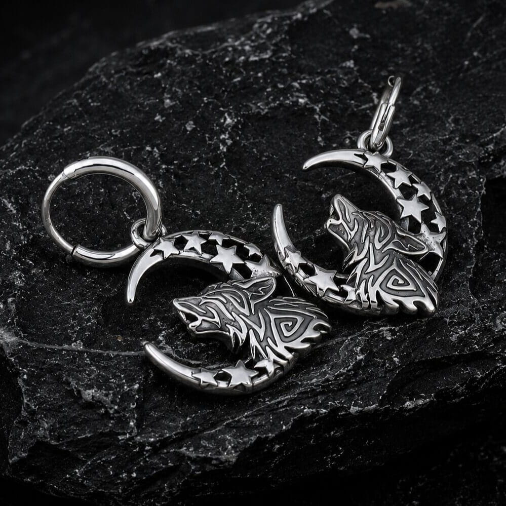 Viking silver wolf and moon hoop earrings with knotwork and star cutouts on dark rock.