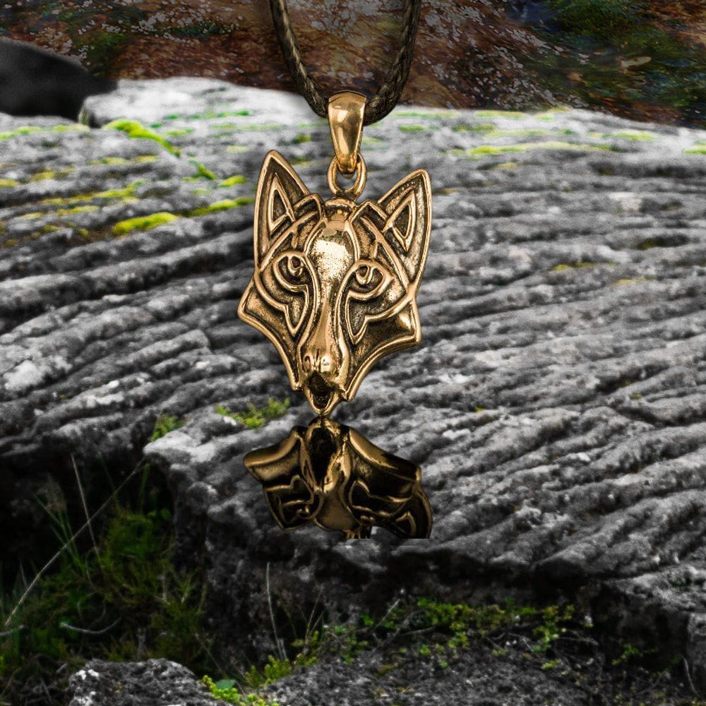 Handmade Viking wolf pendant in bronze, featuring intricate Celtic knotwork, resting on dark stone.