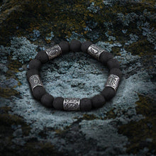 Viking volcanic stone bracelet with silver steel Futhark rune beads on a mossy rock.