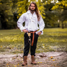 Viking-style white cotton long-sleeve shirt with ruffled neckline & wrists, worn by a man in a park.