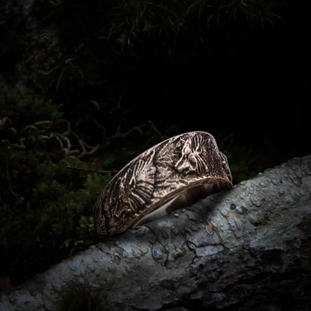 Handmade sterling silver Viking wolf ornament ring with intricate Norse design on a tree branch.