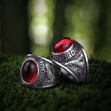Viking silver signet rings with large red oval gemstones, intricate raven and Futhark carvings.