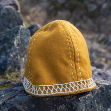 Mustard yellow wool Viking cap with white embroidered stitching and a decorative band.