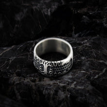 Sterling silver Viking Yggdrasil symbol ring with intricate tree and root design on dark stone.