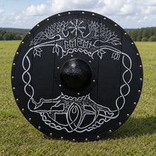 Black Viking round shield 22-inch with white Yggdrasil world tree, Helm of Awe, and Runes design – brass rivets and metal boss on grass field