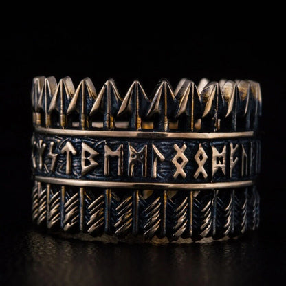 Handcrafted Viking bronze ring featuring three bands – top row of Tyr arrow symbols, center band with complete Elder Futhark runic alphabet, bottom band with diagonal chevron feather pattern – oxidized black finish with raised bronze details