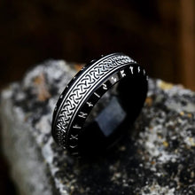 Black Rune Celtic Knot Stainless Steel Ring featuring silver Elder Futhark alphabet on edges and woven Celtic braid pattern on center band displayed on stone