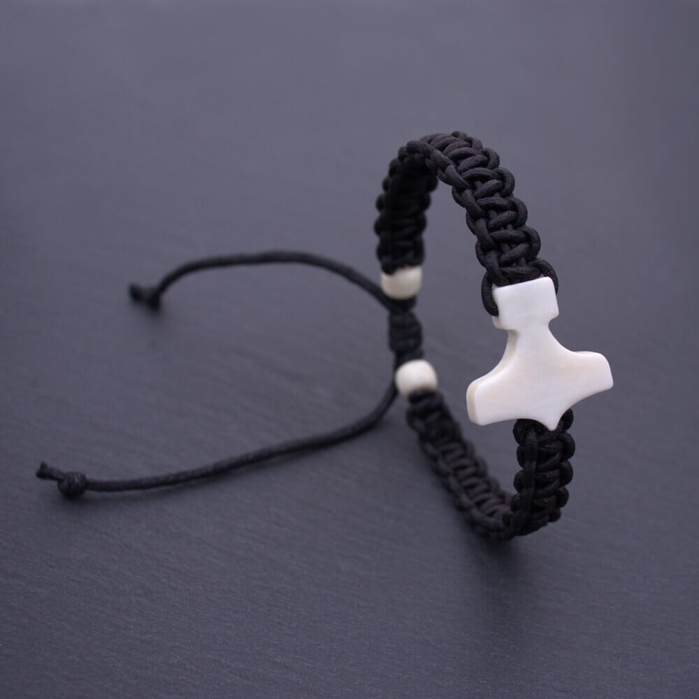 Black cord braid bracelet featuring a Thor’s Hammer bone-white pendant, styled with sliding knots and bead accents.