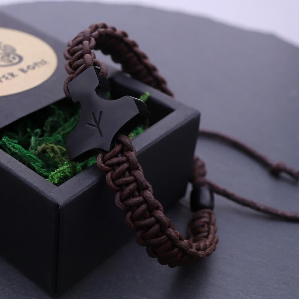 Thor’s Hammer Bone-Black Pendant Braid Bracelet displayed on a black gift box filled with green moss.