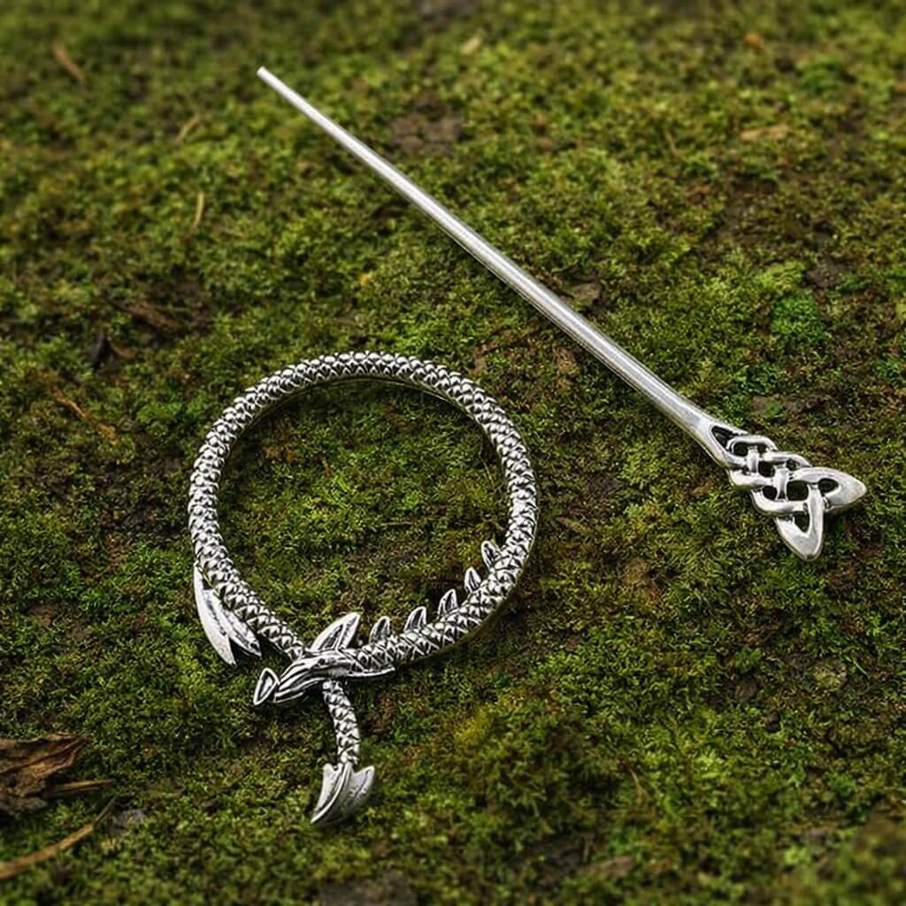 Silver Viking dragon ring hair clip with a Celtic knot pin on moss.