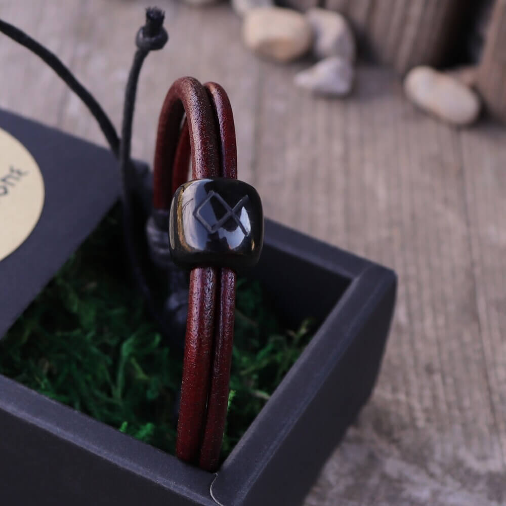 Burgundy Viking Horn Rune Leather Bracelet with black rune bead, displayed in a gift box on rustic wood.