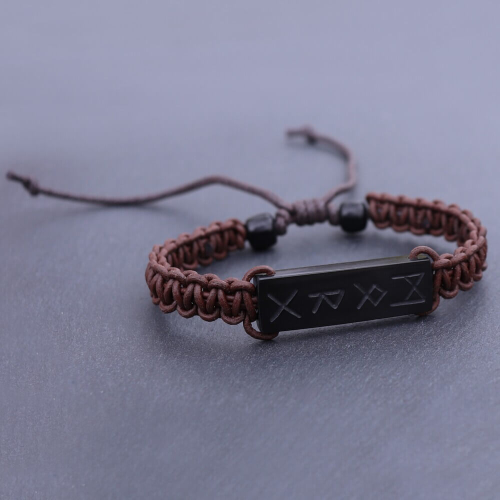 Handwoven brown cord bracelet featuring a black buffalo horn plate engraved with Viking runes.